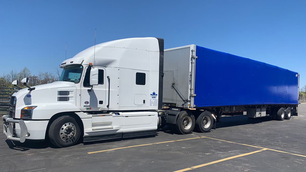Blue trailer truck for rolltite transport services - weather protection with flatbed accessibility